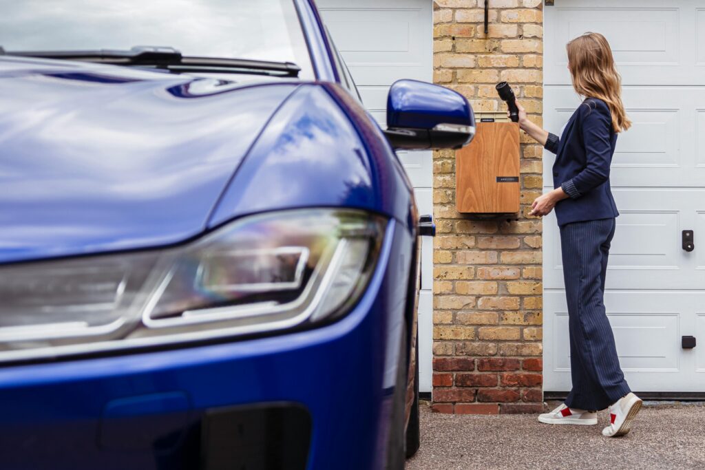 Woman charging an electric car at a home station, promoting sustainability.